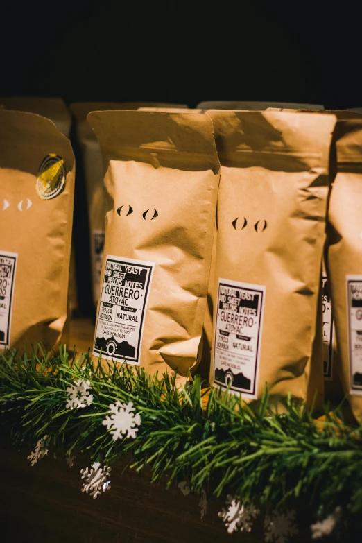 some bags of coffee next to pine nches and flowers