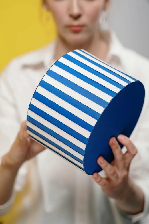 a young woman holding up a striped, round object