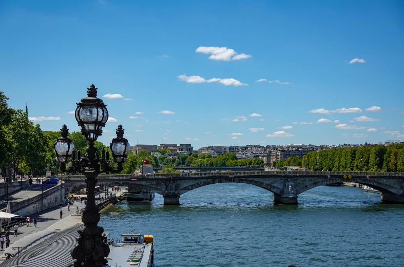 an old bridge on the river with a light post and street lamps near it