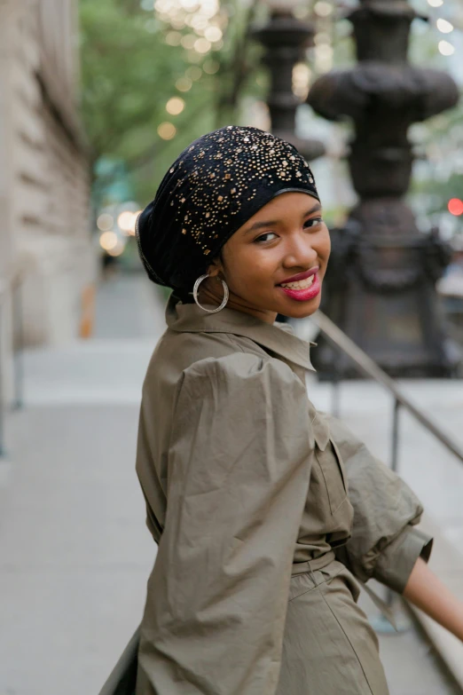 a smiling woman in a headscarf on the sidewalk