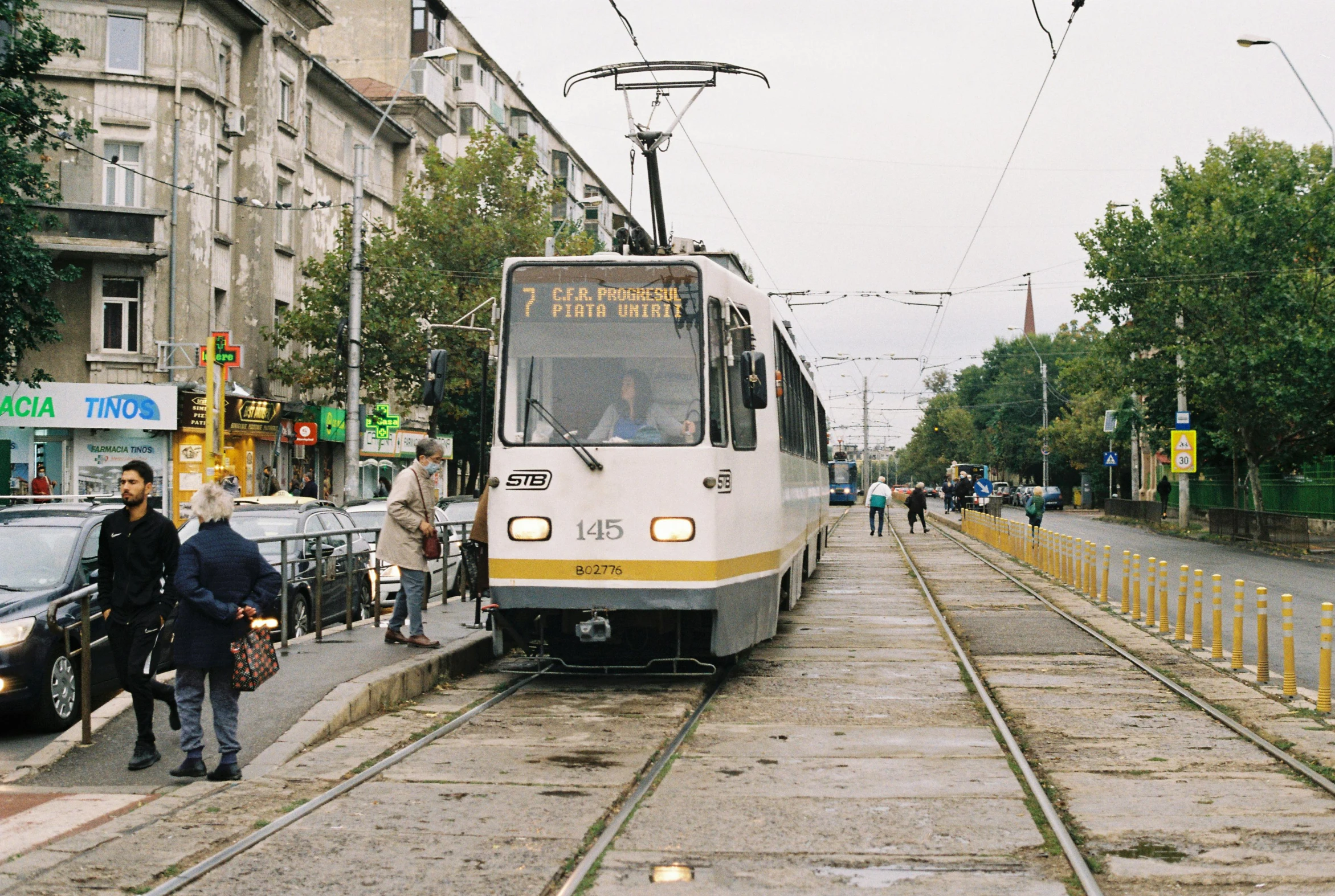 a trolley car with people exiting it next to the track