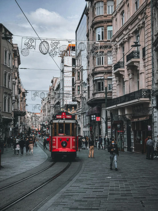 a red trolley and people on street next to buildings