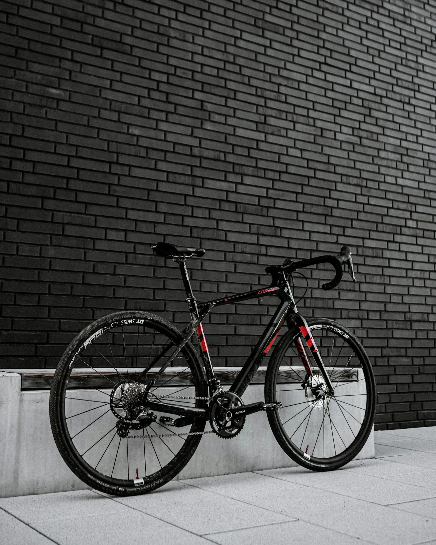 a bicycle leaning on a curb in front of a brick building