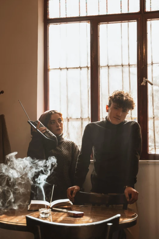 two people sitting at a table with a smoke stick and cigarette in front of them