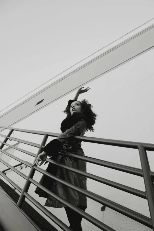 a woman wearing a coat is standing on a stairwell