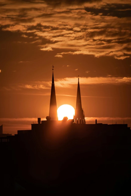 an image of a sunset that is behind buildings