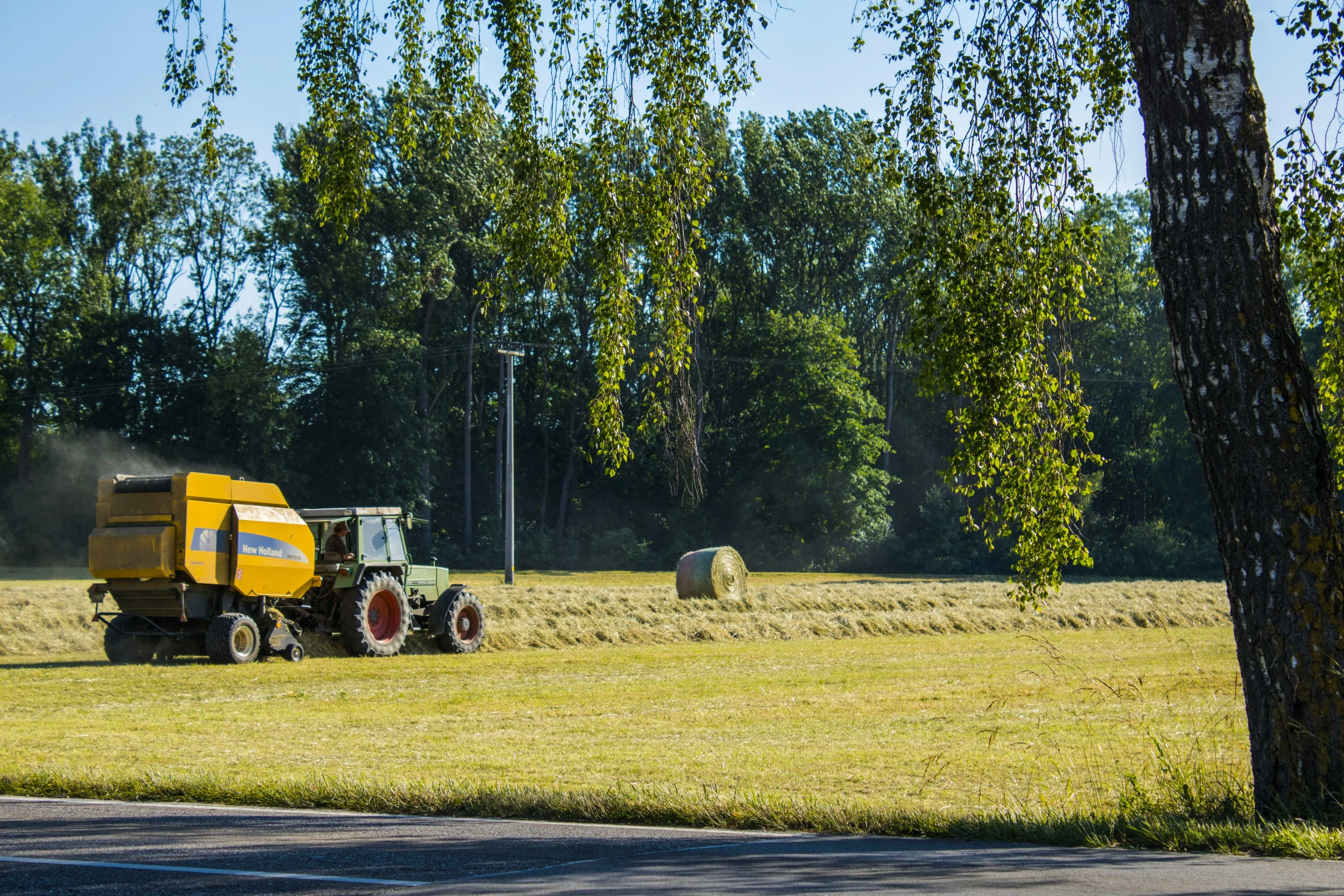 some hay being loaded onto a trailer by two tractors