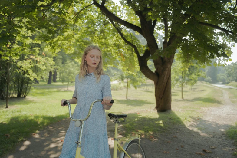 a little girl on her bicycle standing in a park