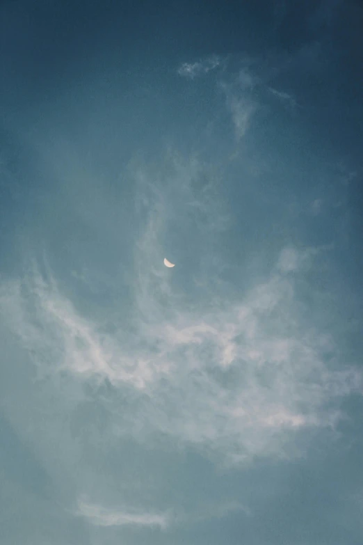 the moon is visible in the sky on a partly cloudy day