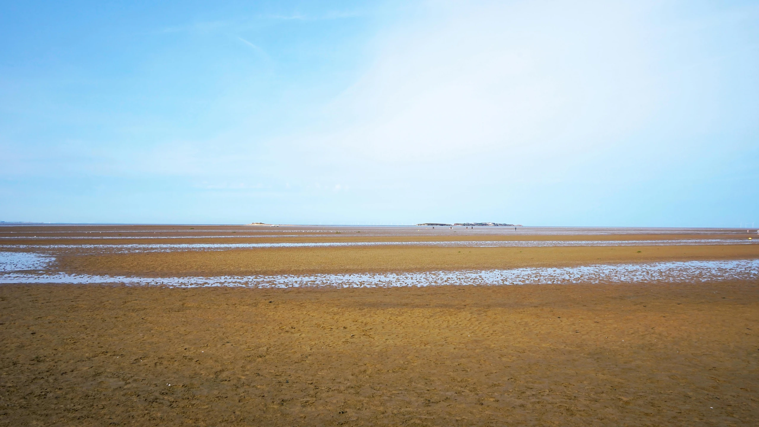 a beach on a sunny day with small waves