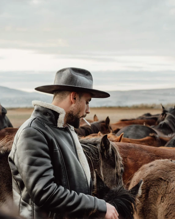 a man stands near horses in a herd