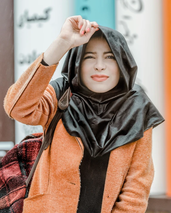 a woman is standing outside in an orange jacket