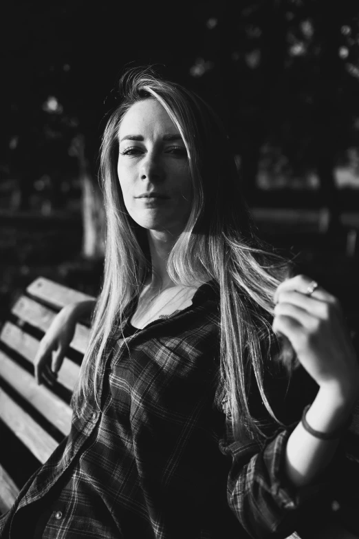 a woman sitting on top of a wooden bench next to trees