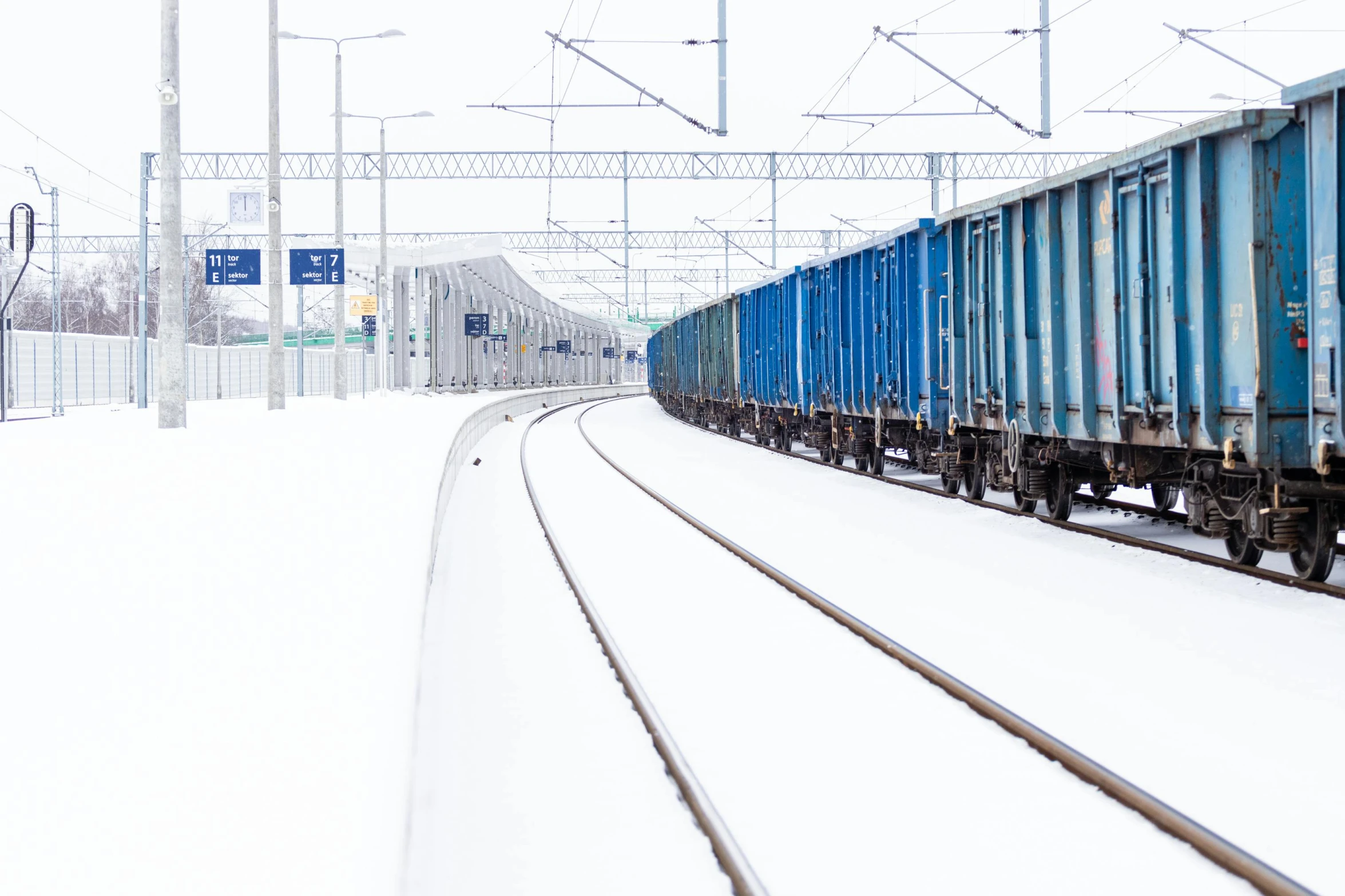 a train traveling past a passenger loading platform in the snow