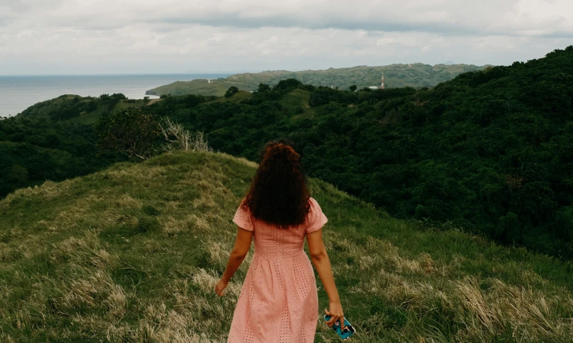 a woman in pink dress walking down a hill