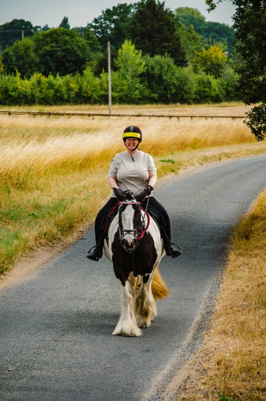 woman riding on the back of a white and brown horse