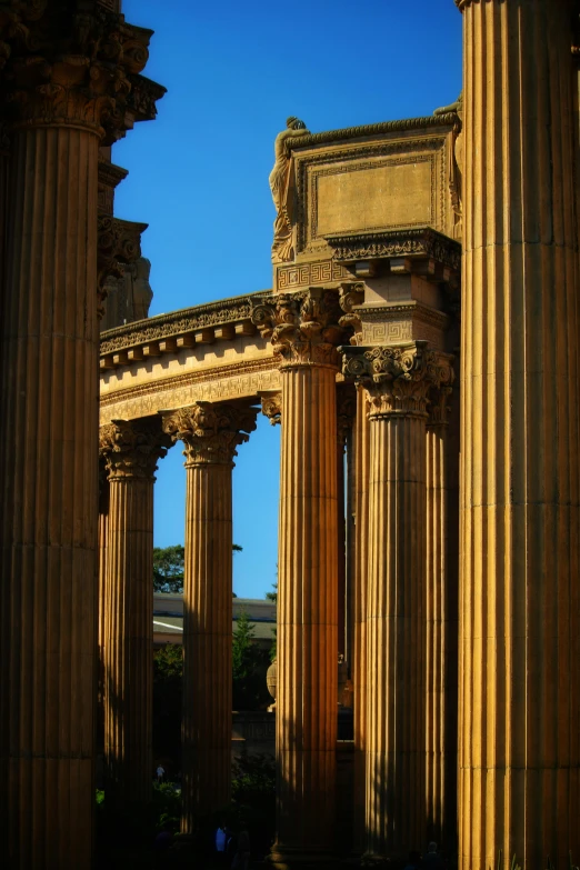 an old building with columns and two people walking by