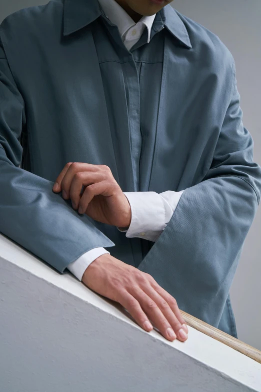 a person in a grey suit leans on a ledge