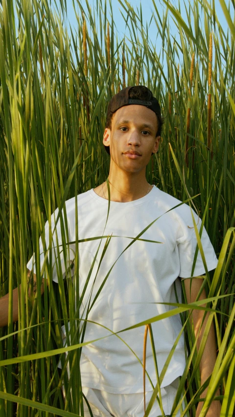 the young man is standing amongst tall grass