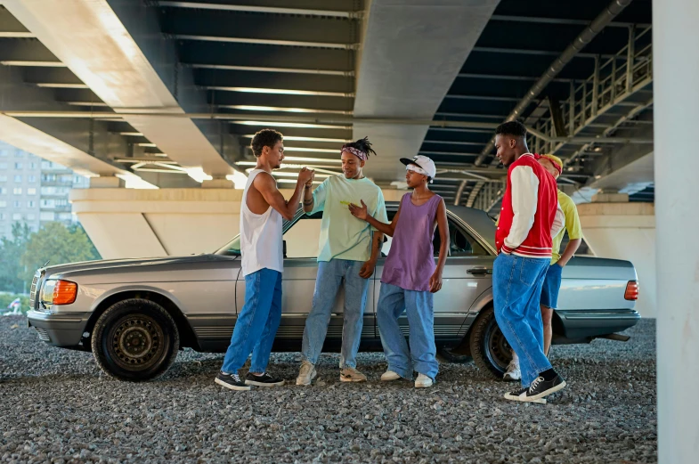 four young men standing next to each other near a car