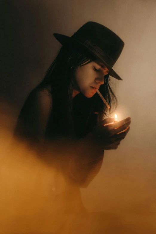 woman with cigarette wearing a hat and holding a lit candle