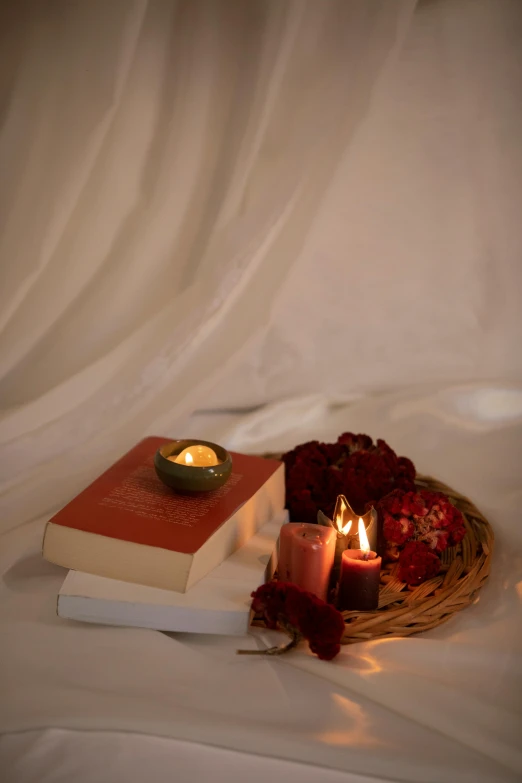 two candles are placed next to a book and some roses