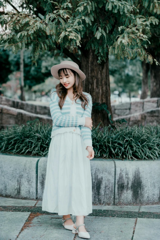 a young woman wearing a hat in front of a tree