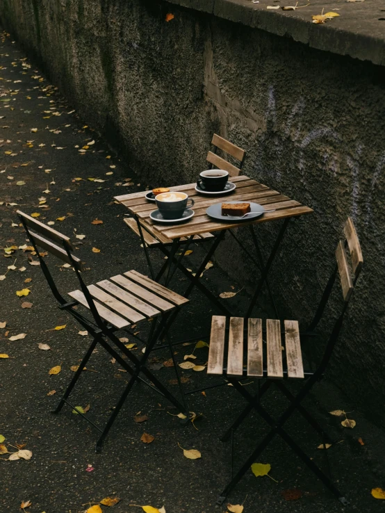 a set of table and chairs near wall with autumn leaves