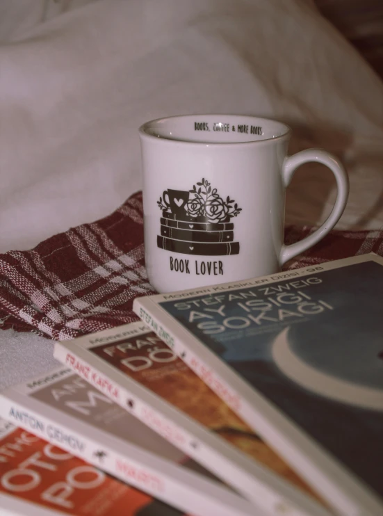 the mug sits beside some books on the bed