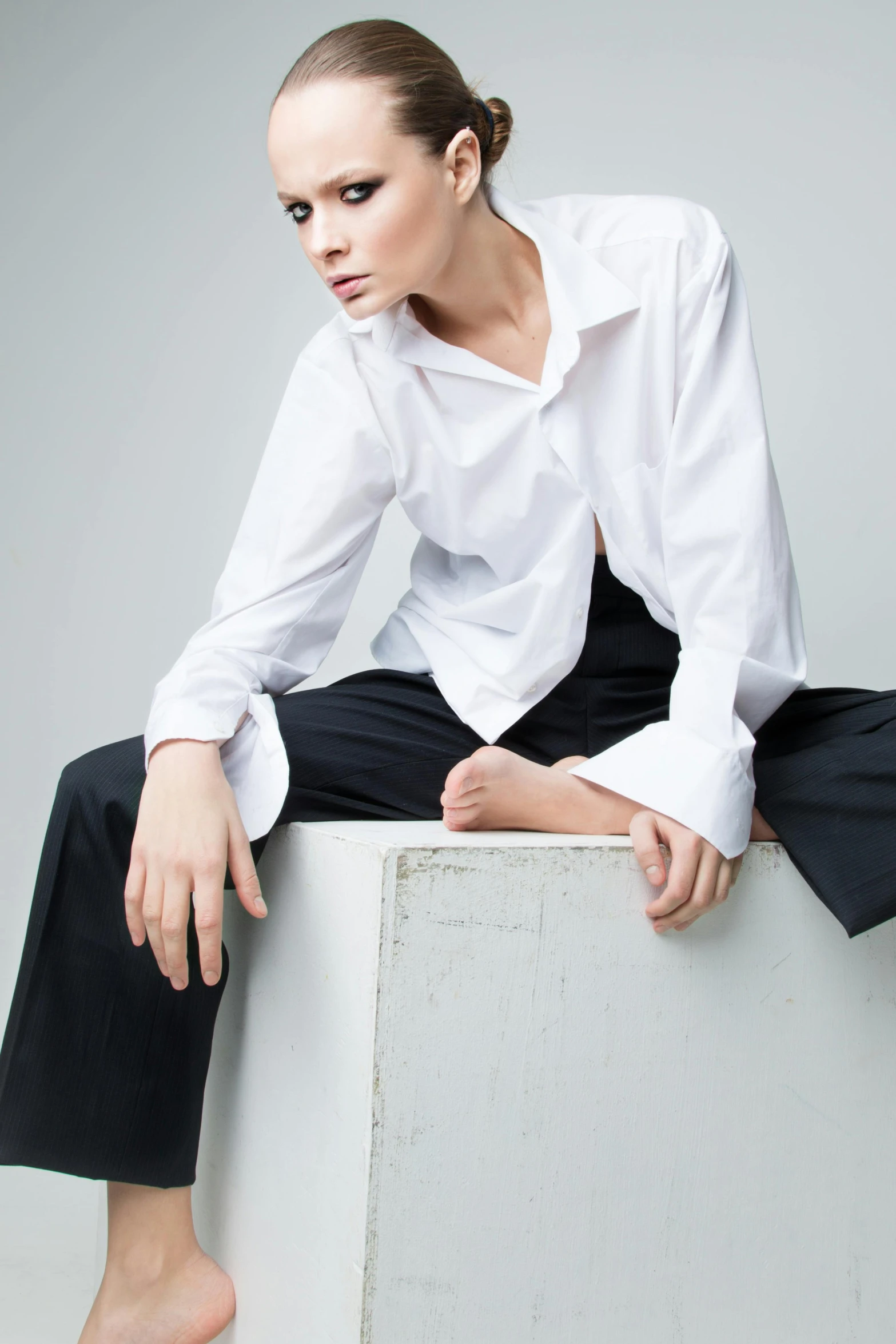 a woman in a white shirt is posing with her foot on the edge of a box