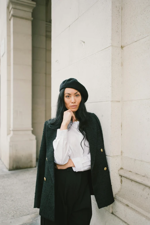 a woman in a hat is standing on a sidewalk