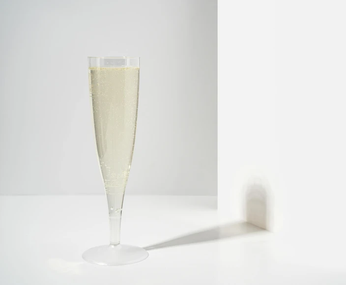 a champagne glass with liquid inside sitting on a white table