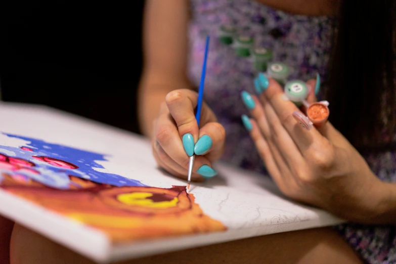 the woman is using some blue and orange nails