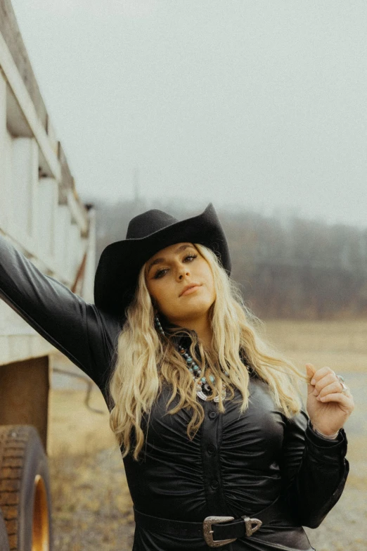 a woman with a black hat standing next to a trailer