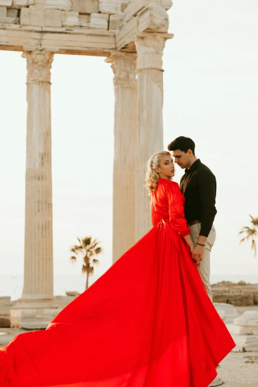 a woman in a long red dress next to a man