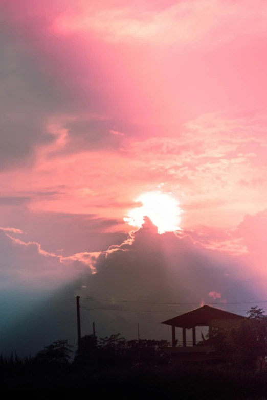 the sun shining behind clouds over an old structure