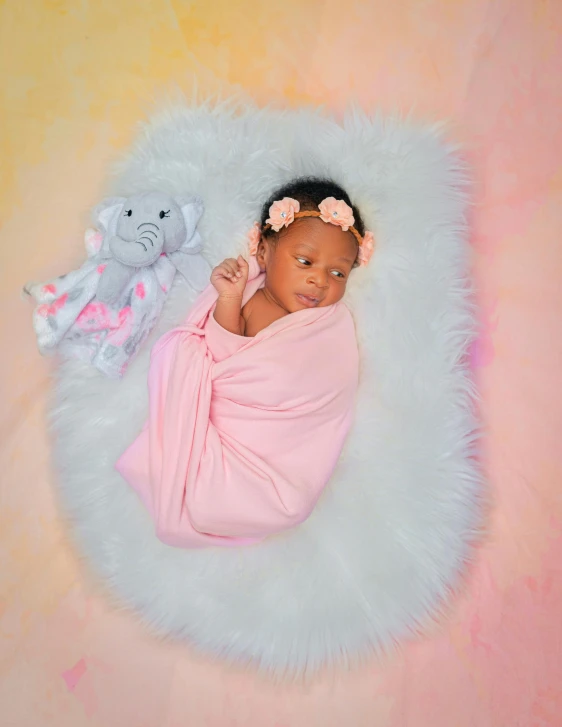 baby in pink wrap and bear laying on fur