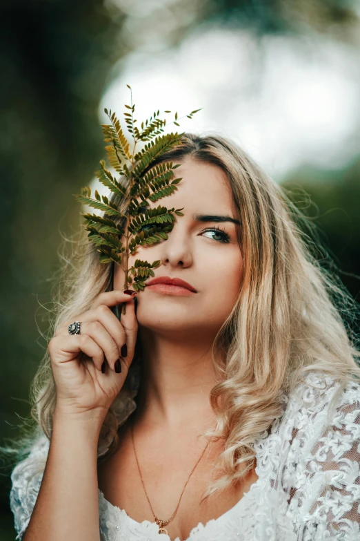 a woman is holding up a fern nch in her hand