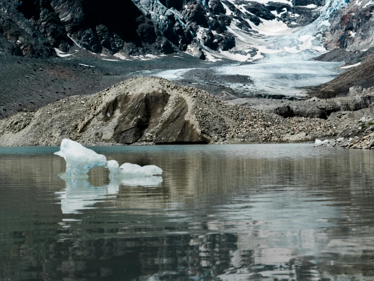 an iceberg floating on top of water surrounded by mountains