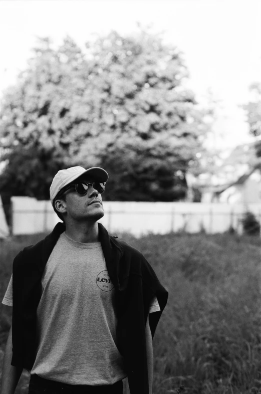 a man standing in a grassy field in front of trees