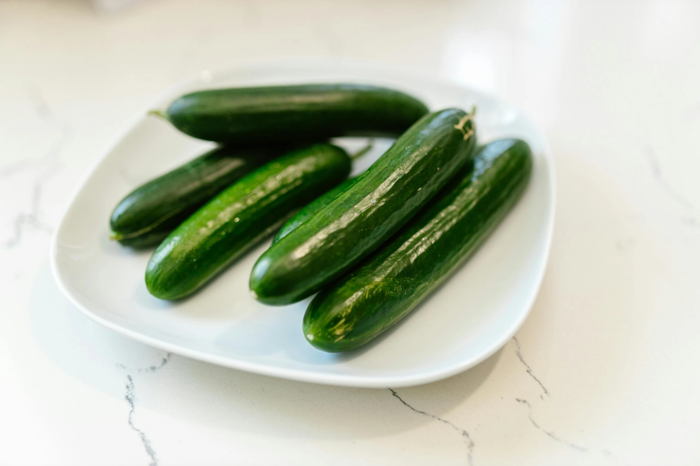 several green cucumbers on a plate sitting on a table