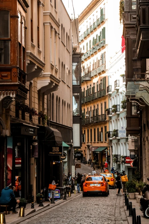 people walking down the street, cars parked on either side of the road