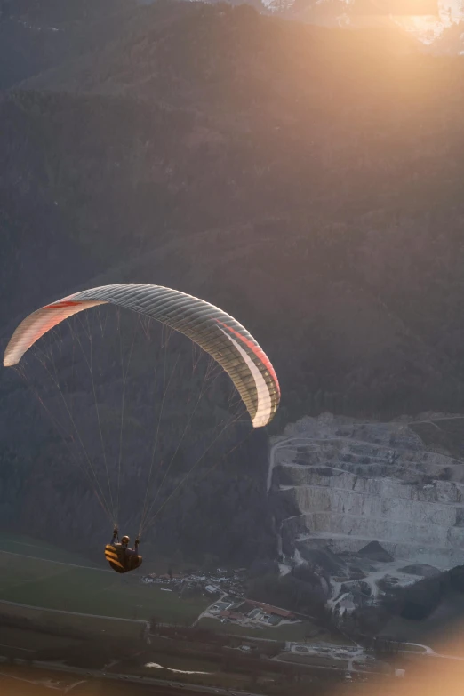 a parasail glides over a cliff in the mountains