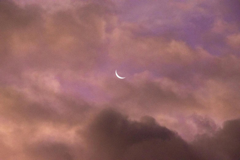 a cloudy purple sky with a moon on top