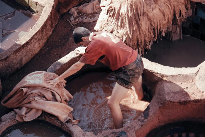 a man in a red shirt works on clay