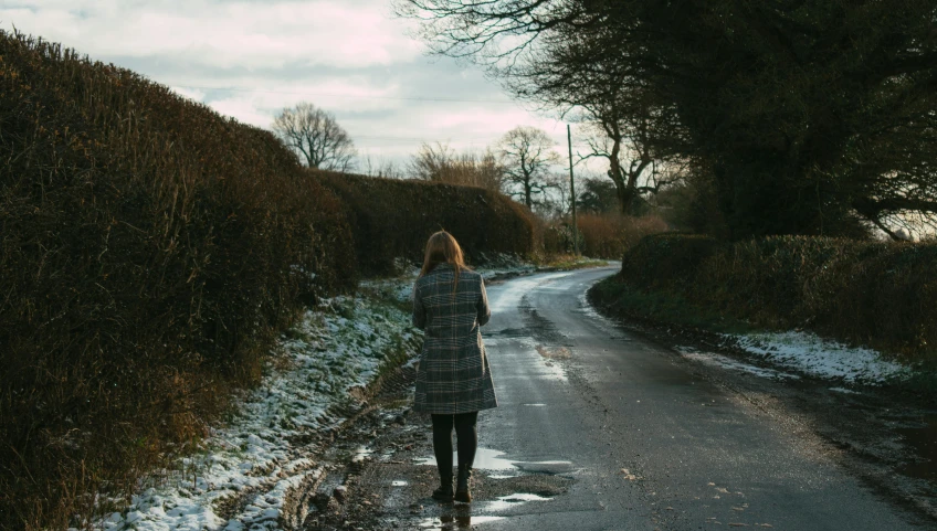 a woman walking in the road with an umbrella