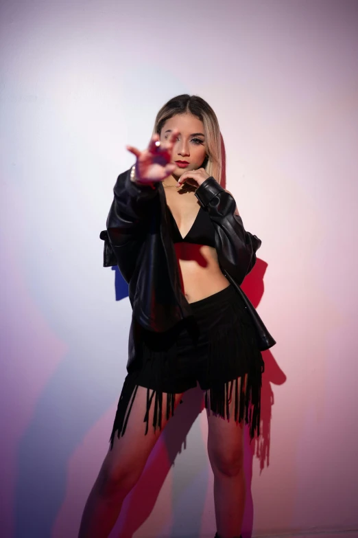 young woman in black outfit posing in front of white wall