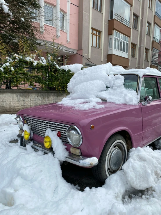 the pink car is parked in the thick, heavy snow