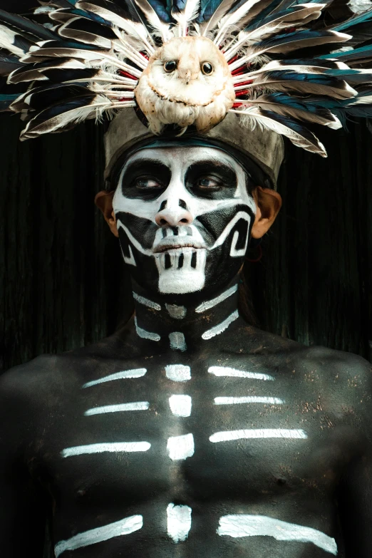 a man in black painted body paint with feathers on his head