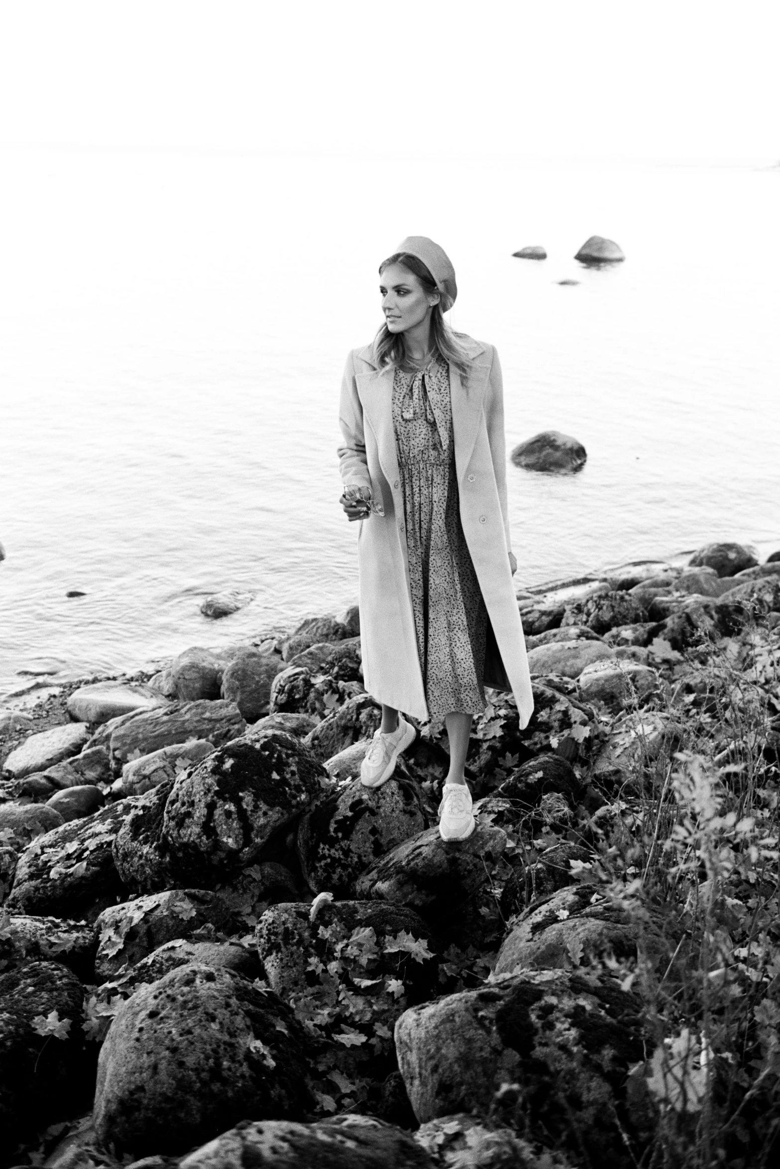 woman walking on a rocky beach next to the water